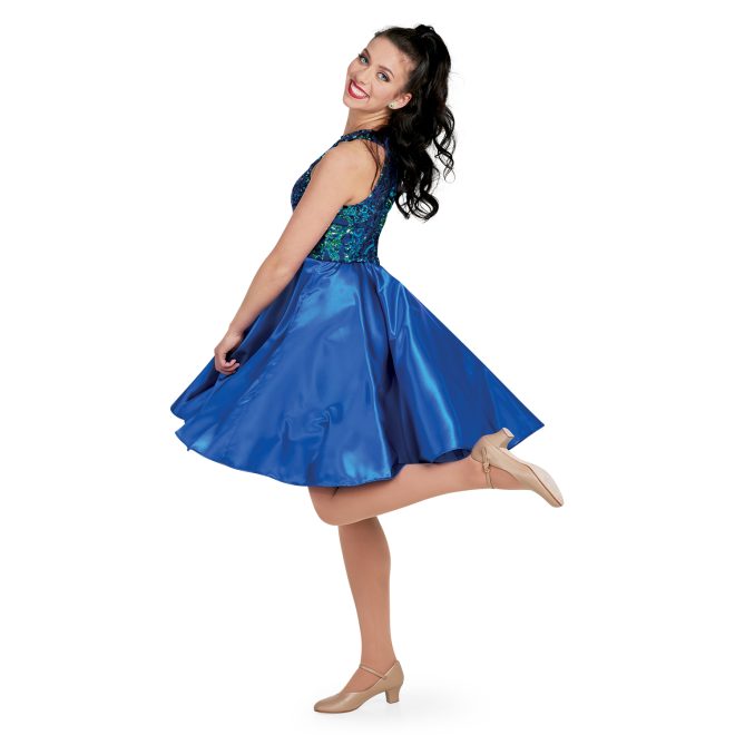 custom show choir dress with goddess neckline in navy irid/ navy sophisticated sequin with flowy knee length skirt on model back/side view