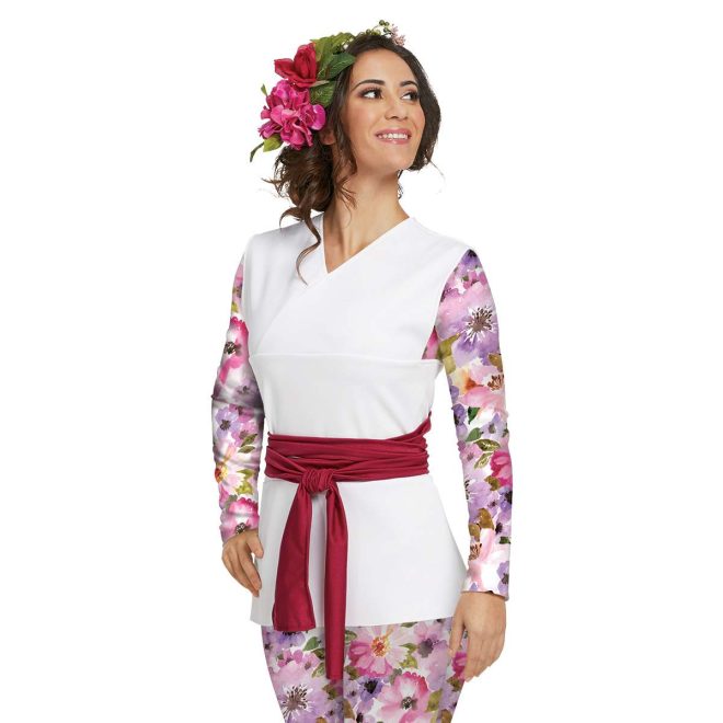 Custom long sleeve color guard capri unitard with tunic over. Unitard is purple and pink floral with white background. Tunic is solid white sleeveless with red belt around waist. Front view on model with red and pink flower in hair