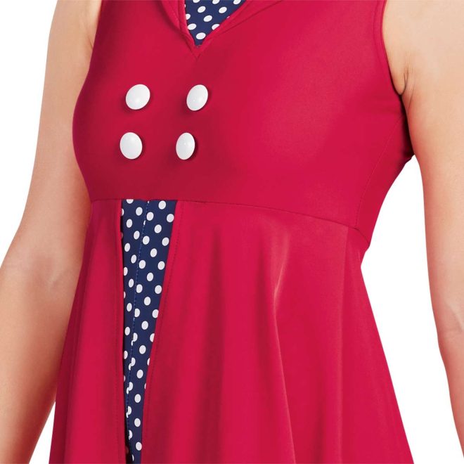 Close up of custom sleeveless color guard knee length dress. Solid red dress with navy with white polka dots in V on chest and attached boy short underneath. Front view on model with 4 white buttons on chest