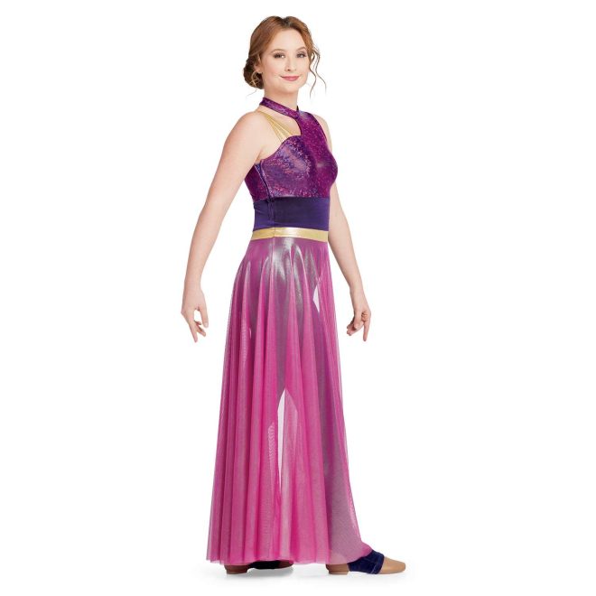 Custom sleeveless legging color guard unitard. Right shoulder has three thin gold straps and cutout from neck. Left shoulder, neck and chest magenta sequin. Pants are velvet purple with magenta mesh partial floor length skirt with gold band around waist. Side view on model