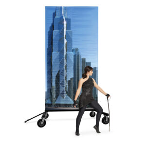 band shoppe prop cart holding scene of tall buildings with performer in front wearing black uniform holding sabre