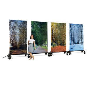 prop cart printed media with scenes of each season of tree lined road with performer in front in white and grey uniform