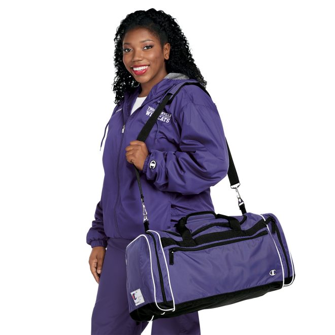 purple, black and white champion all around duffle bag worn over shoulder on model wearing purple jacket and pants side view